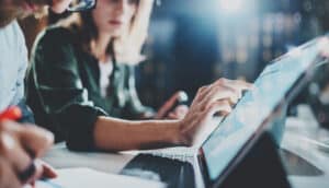 woman pointing on digital tablet screen at night office