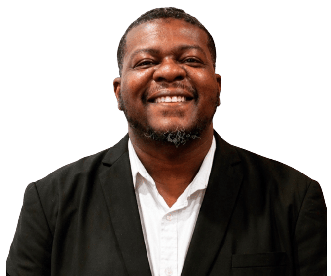 Smiling man in a black suit and white shirt, head and shoulders portrait against a dark background.